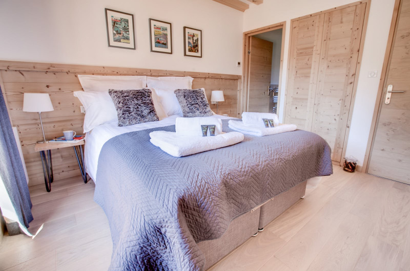 Chambre avec lit double, esprit chalet moderne avec du bois clair des murs blancs et une décoration raffinée